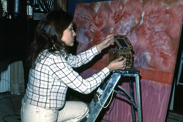 The artist works in front of a painted canvas.