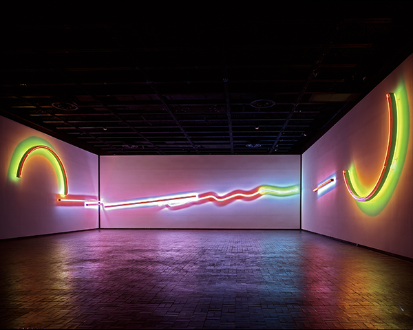 A neon line crosses and arcs around the walls of a dark gallery.