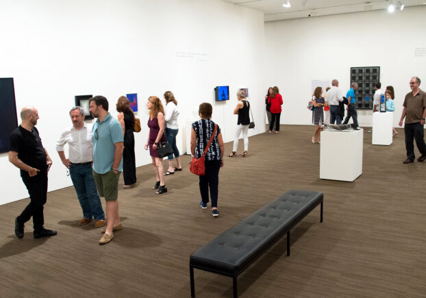 A crowd enjoys an exhibition preview in the gallery.